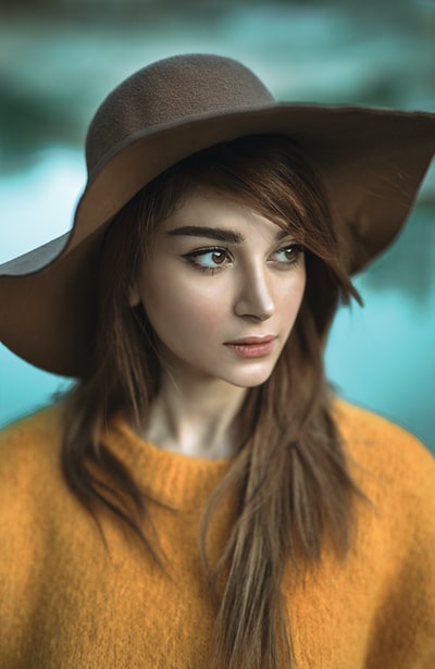 In a yellow sweater, wearing a brown hat of the woman looked at her right side

